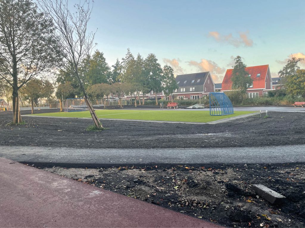 Afbeelding van het voetbalveld. Rondom het veld is asfalt aangelegd. In de achtergrond op de afbeelding is het skatepark te zien.