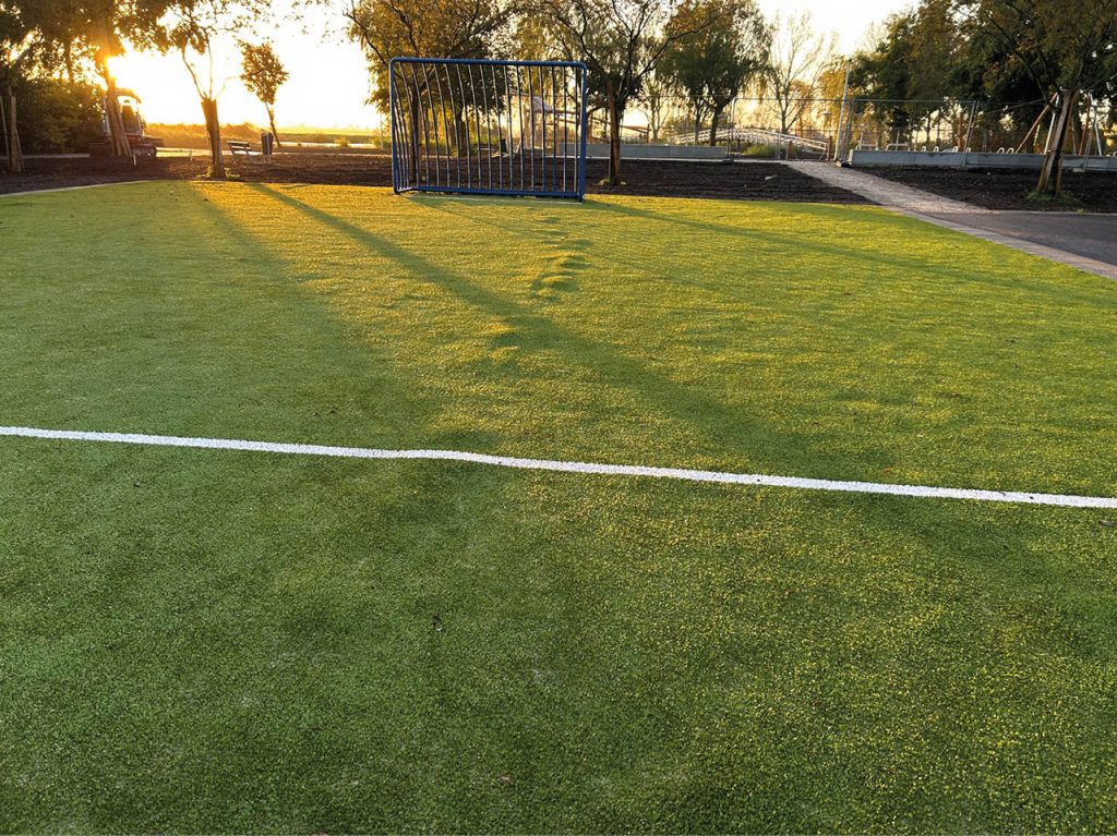 Op de afbeelding is het voetbalveld te zien. Onder het kunstgras heeft een mol een tunnel gegraven. Deze tunnel is te zien in het kunstgras.